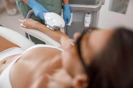 Closeup of hair removal procedure on arms with ipl machine from a professional cosmetologistの写真素材