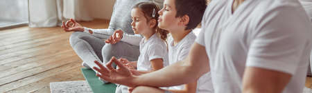 Parents doing meditation with kids at homeの写真素材
