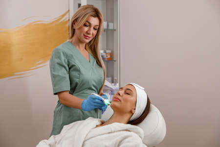 Professional cosmetologist or dermatologist providing aesthetic skin treatment in beauty spa salon