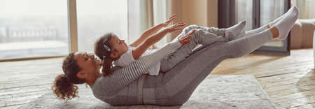 Happy woman exercising with daughter at homeの写真素材