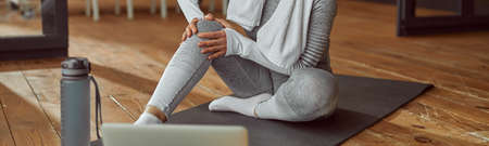 Slim woman hurting knee during online training