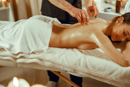Professional male therapist doing vacuum massage with the special cups. Chinese massageの写真素材