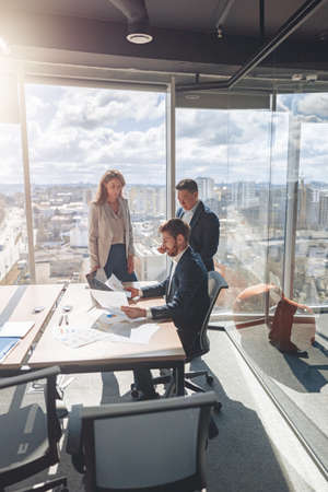 Team of young businessmen working and communicating together in modern office with panoramic windowsの写真素材
