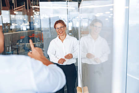 Successful smiling lady boss listens to employees comments during business meeting