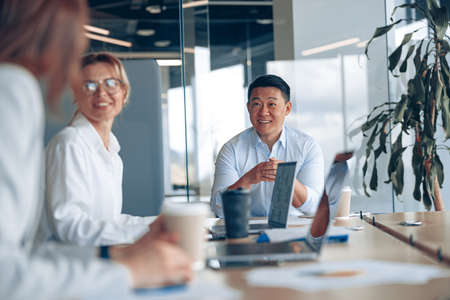 Young Asian businessman listening his colleagues on meeting in modern officeの写真素材