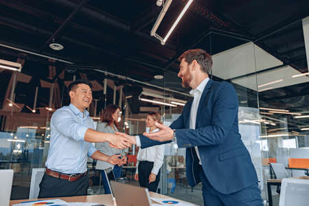 colleagues are shaking their hands in modern office during teamwork meetingの写真素材