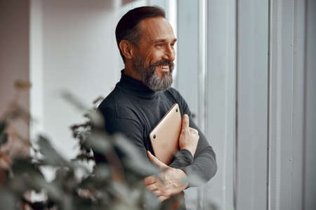 Happy adult caucasian man standing in a modern office
