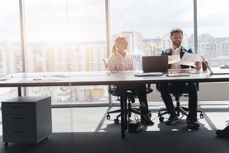 Two middle age confident business workers. Working together with smile on face using laptop