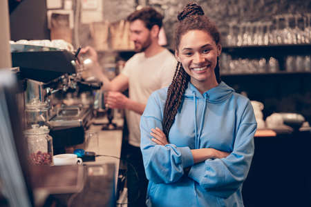 Beautiful young stylish woman barista standing at bar coffee machine and smiling. cafe worker.の写真素材
