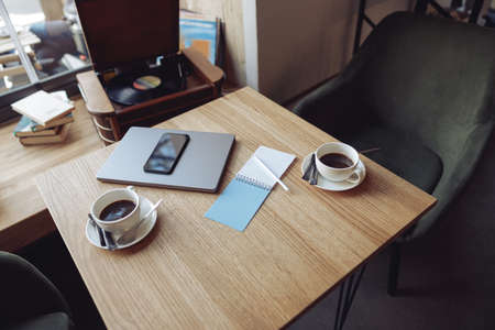 View from above on table with two white cups of coffee and business stuff. Laptop and phone.