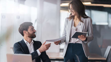 Smiling secretary brought the documents to the boss to sign