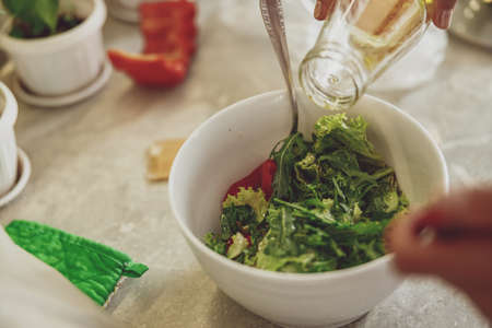 Closeup of process of adding olive oil to green saladの写真素材