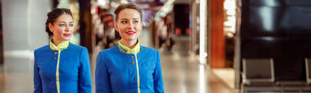 Female flight attendants carrying travel bags at airport