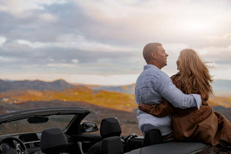 Back view of smiled happy couple embracing and laughing outdoor together during tripの写真素材