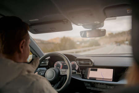 Rear of man driver driving a car, shot from inside the car, traveling in automobile