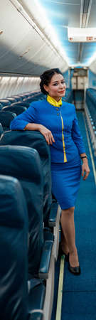 Female flight attendants standing in aircraft passenger cabin