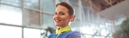 Cheerful woman airline worker standing in airport terminalの写真素材