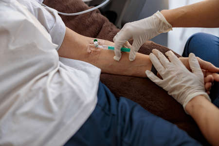Nurse putting a drip in the arm of her patient in modern medical clinic