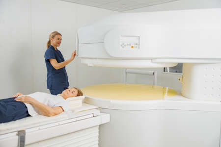 Radiologist controls MRI or CT or PET Scan with female patient undergoing procedureの写真素材