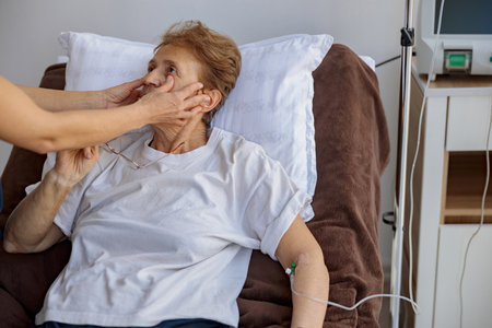 Doctor checking the pupils of a female patient during treatment in a hospital ward