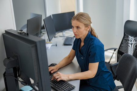 Nurse on Duty working on computer at the Reception Desk in modern clinicの写真素材