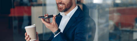 Handsome businessman is using smartphone to record a voice message to business partnerの写真素材