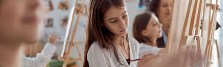 Young creative happy pupils at light modern classroom are doing drawing lessonの写真素材