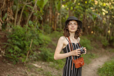 Pretty young woman holding photo camera while traveling in Africaの写真素材