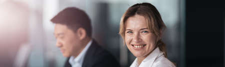 smiling businesswoman sitting at the office with colleague on backgroundの写真素材