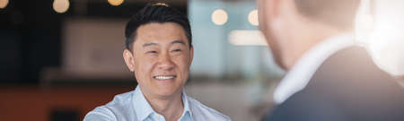 Close up of two smiling businessmen are handshaking after a successful deal in modern office