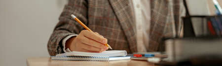 Close-up of unrecognizable business woman taking notes in notebook