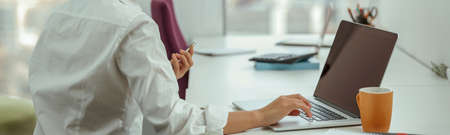 Pretty asian business woman working laptop and holding phone sitting in modern office