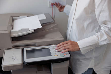 Close up of woman worker scanning a document on photocopy machine In modern office