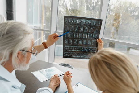 Team of doctors discuss results of X-Ray or MRI scan of patients spine in medicine office of clinic