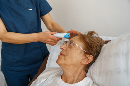 Close up of doctor measures patients temperature with non-contact thermometer in hospital ward