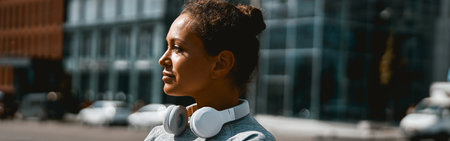Thoughtful sporty woman looking away while standing outdoors in the daytimeの写真素材