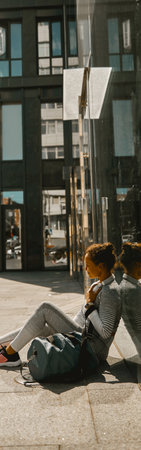 Woman in sportswear sitting leaning against the wall of modern building