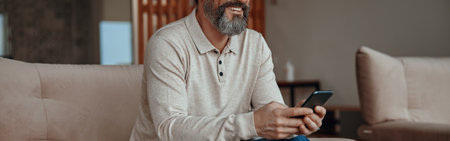 Smiling man sitting in armchair and holding smartphone