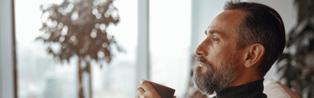 Smiling man sitting in armchair and enjoying hot drinkの写真素材