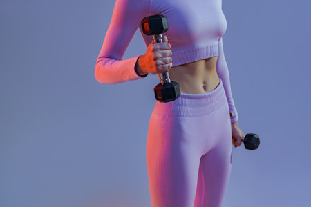 Close up of woman doing exercises with dumbbells on studio background. Strength and motivationの写真素材