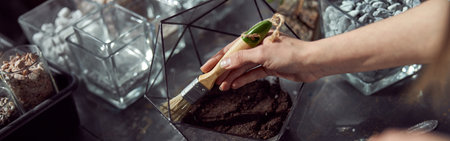 caucasian confident happy florist is working with composition made from glass stones and plants in...