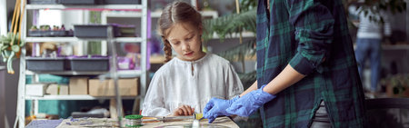 Flourist shop with different kinds of dryed flowers. Young happy confident specialist is working with her female kid.の写真素材
