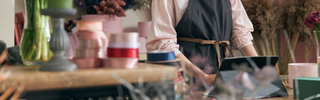 Professional florist young woman is doing bouquets at flower shopの写真素材