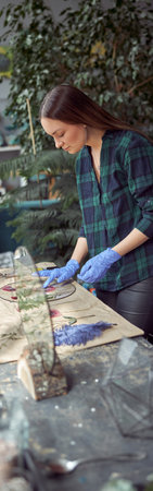Flourist shop with different kinds of dryed flowers. Young happy confident specialist is working with her female kid.の写真素材