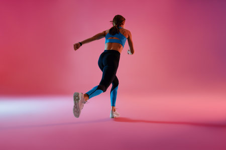 Sporty determined woman running during cardio workout over studio backgroundの写真素材