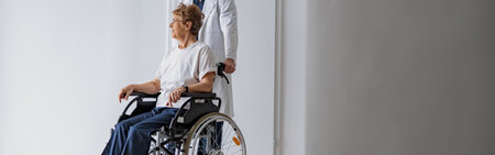 Professional male doctor carrying female patient on wheelchair in medicine clinic hall