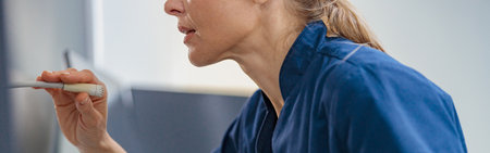 Nurse on Duty makes announcement into microphone sitting at Reception Desk in modern clinicの写真素材