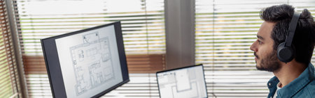 indian male designer in headphones works in home office drawing on graphic tablet