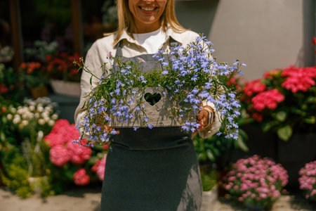 Close up of woman florist business owner standing with houseplant on background of floral storeの写真素材