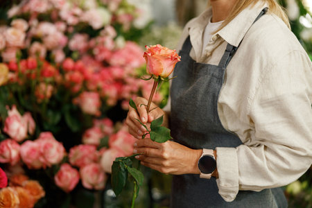 Close up of woman florist flower shop owner hold rose ready to sell on floral backgroundの写真素材